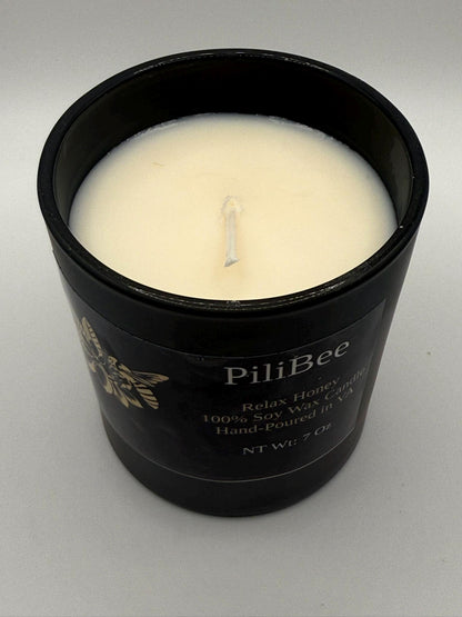 Black candle jar with a white candle inside, labeled 'PiliBee', on a gray background.