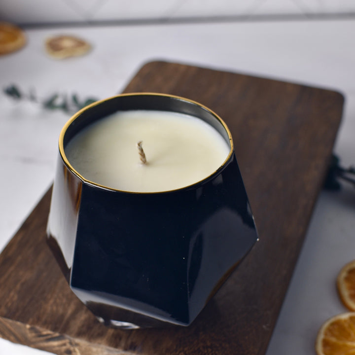 Black hexagonal candle with a white candle inside on a wooden surface