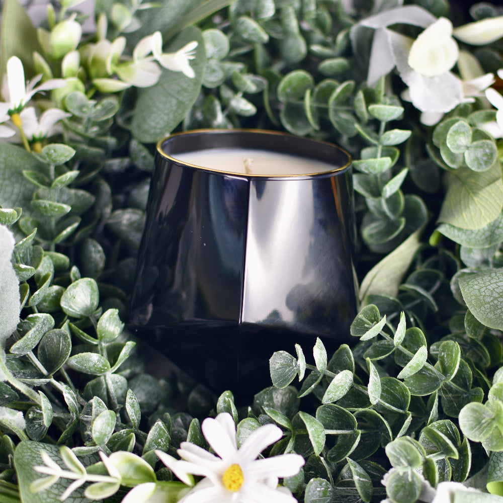 Black candle in a decorative setting with greenery and white flowers