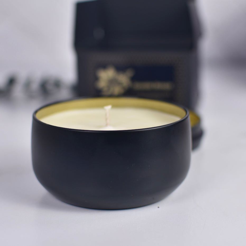 Black candle holder with a lit candle on a white surface, with a blurred background