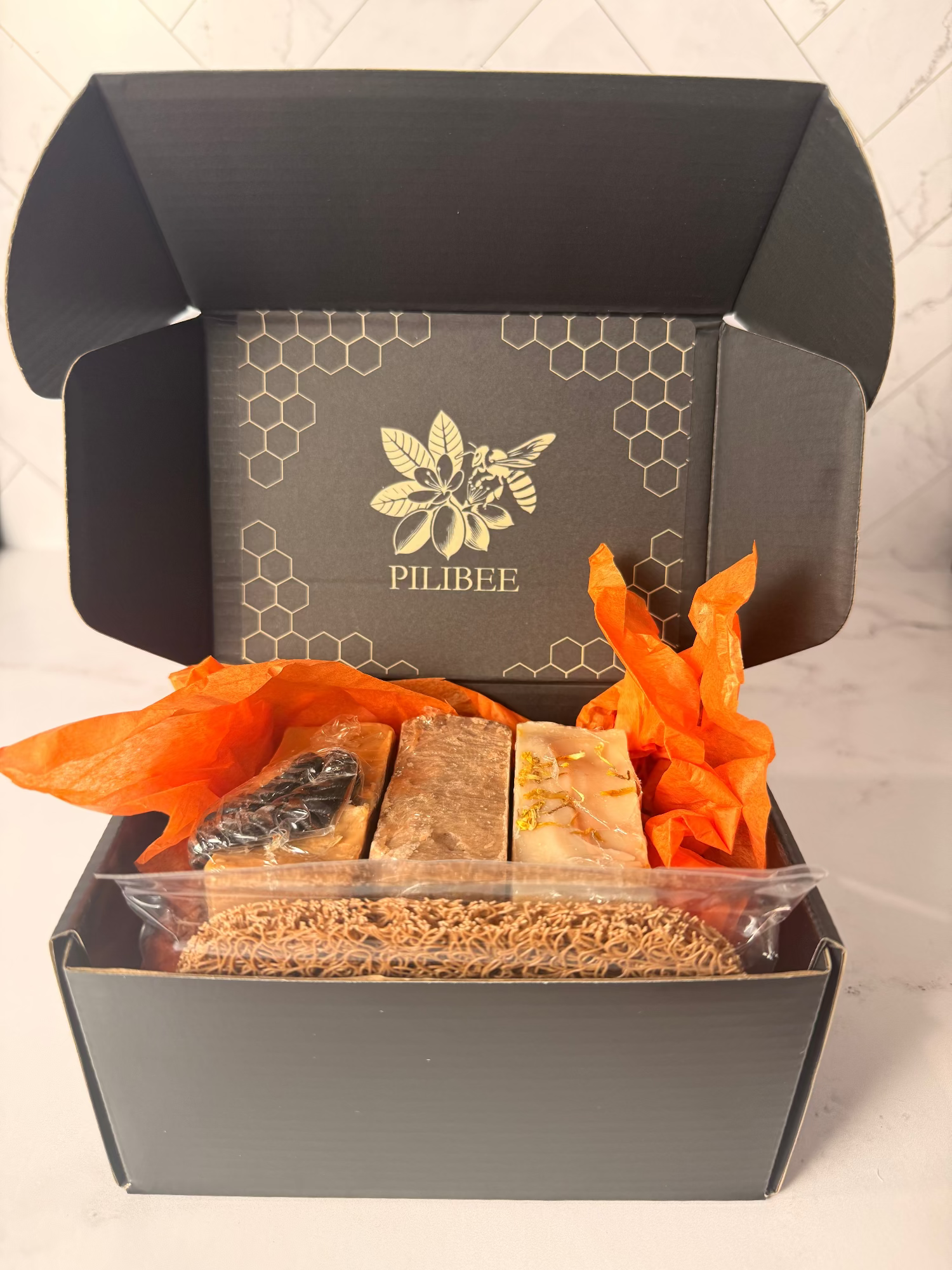 Open box containing various items with 'Pilibee' branding on a light background