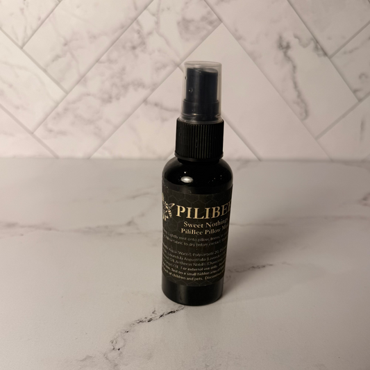 Black spray bottle labeled 'pilibee' on a marble surface with a white tiled wall background