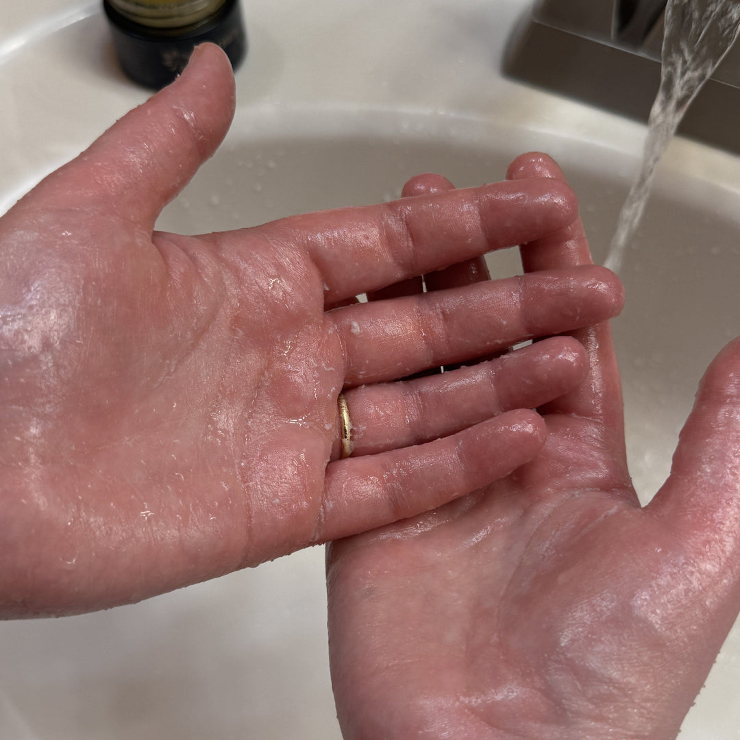 Person washing hands under running water in a sink.