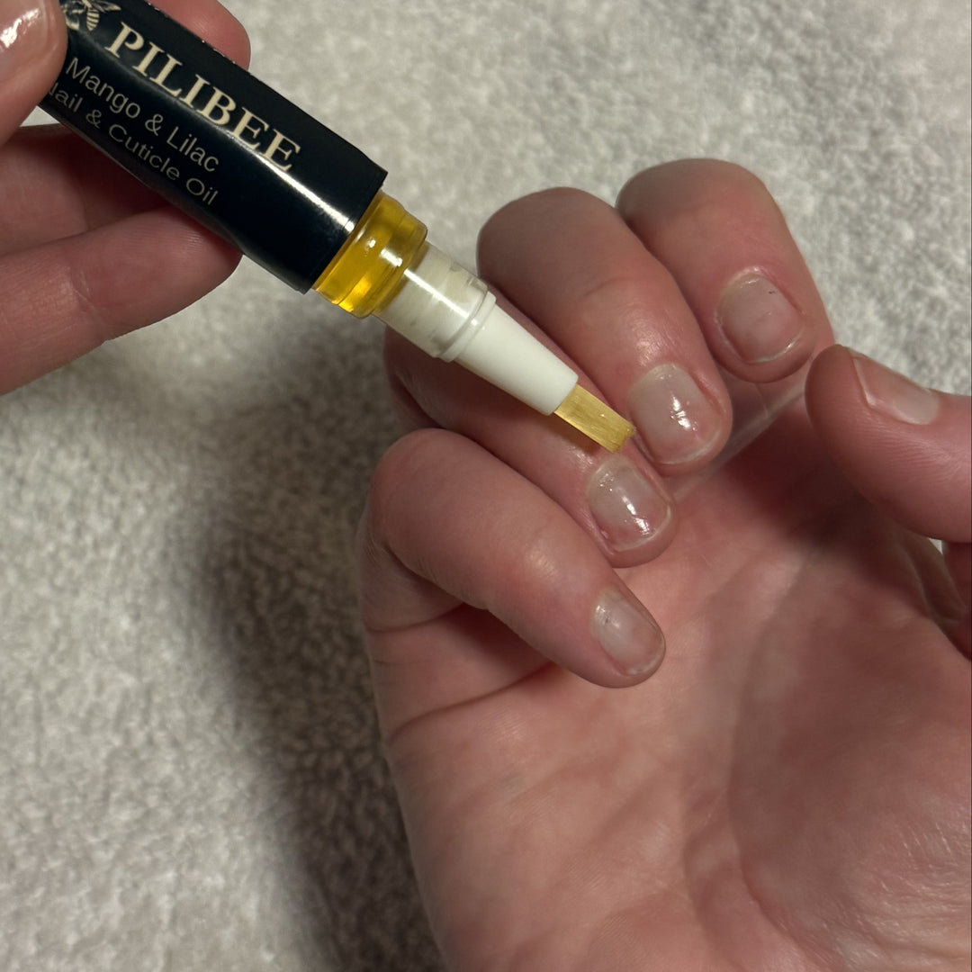 Person holding a small tube labeled 'Pillibee' with a applicator on a light gray background.