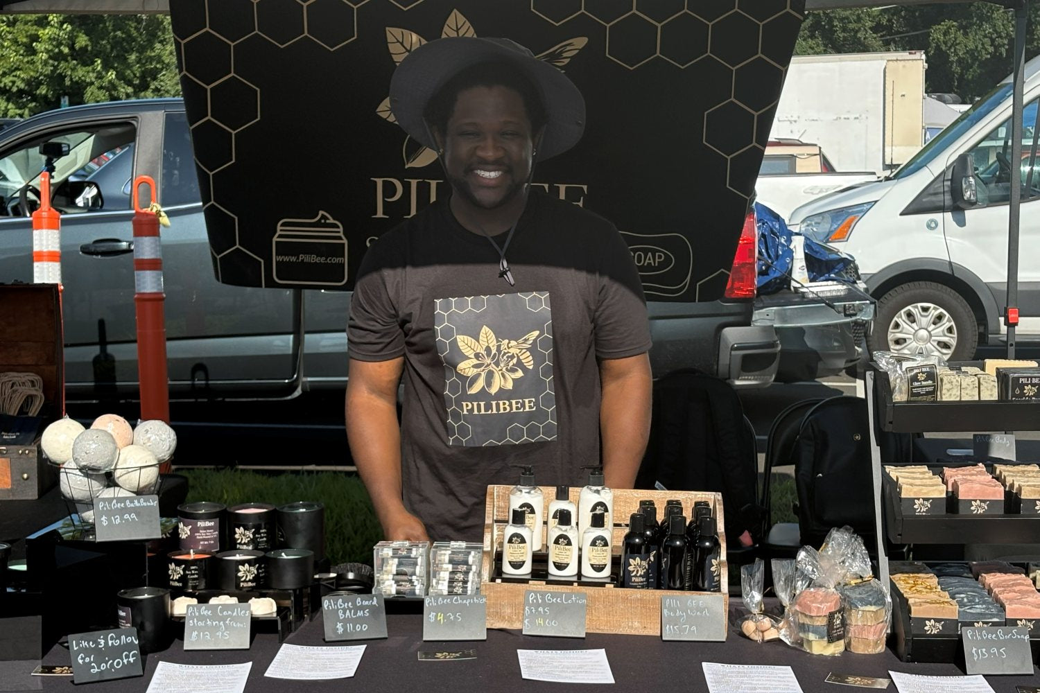 Man standing behind a table with products at an outdoor event, with a branded backdrop.