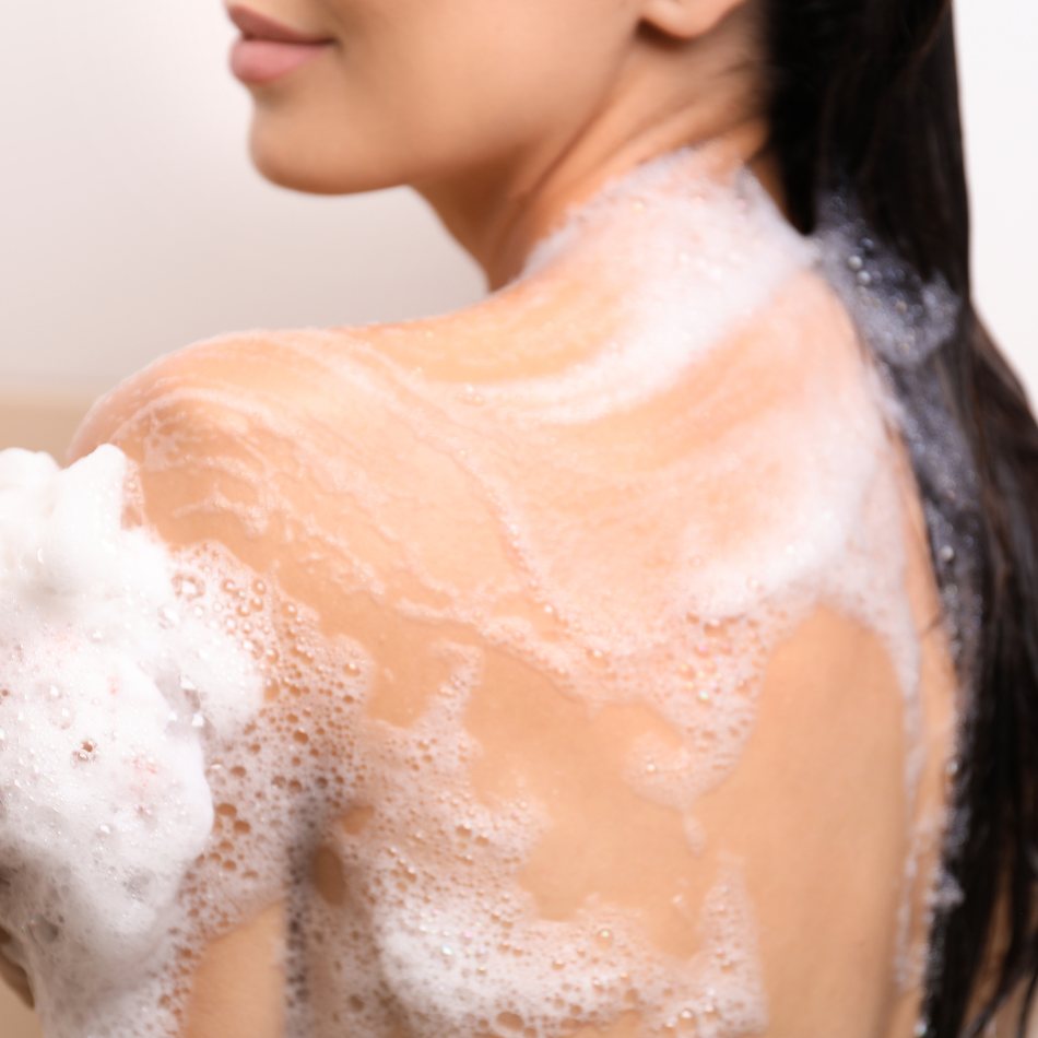 Person with soap suds on their shoulders against a neutral background