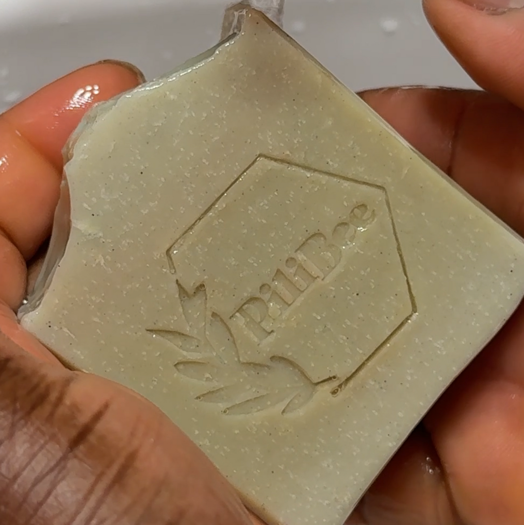 Bar of soap with a brand logo being rinsed under running water from a faucet.